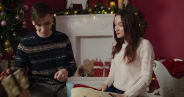 Genç bir çift birbirlerine hediye veriyor ve Noel ağacının önünde sarılıyorlar. Yeni Yıl