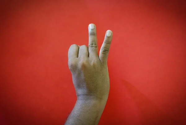 Human showing two fingers count signs isolated on red background