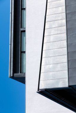 Parlak mavi gökyüzüne karşı fütüristik bir binanın soyut duvar tasarımı.