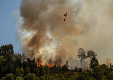 Portekiz 'in Povoa de Lanhoso şehrinde gün boyunca bir orman yangınına karşı savaşan itfaiyeci helikopter..