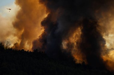 Portekiz 'in Povoa de Lanhoso şehrinde gün boyunca bir orman yangınına karşı savaşan itfaiyeci helikopter..