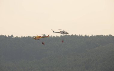 İki itfaiye helikopteri havalanıyor. Bir orman itfaiyesi kurtarma operasyonu sırasında, Povoa de Lanhoso..