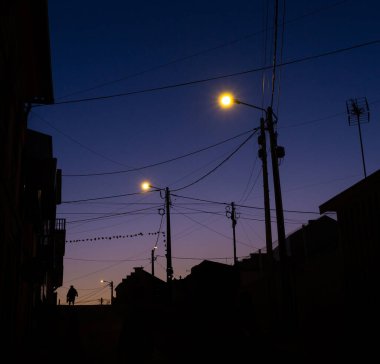 Uzun bir iş gününden sonra eve dönen bir adam, mor gün batımında sahne siluetleri, Aveiro, Portekiz.