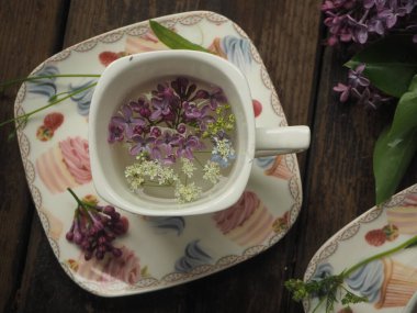  Masanın üzerinde leylak yaprakları olan Fransız bardağı. Fransız tarzı leylak dalları