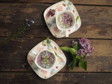 Masanın üzerinde leylak yaprakları olan rench cup. Fransız tarzı leylak dalları