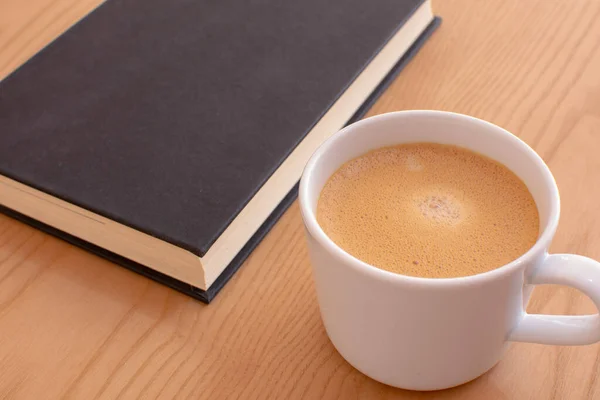 coffee cup with book on wooden table background