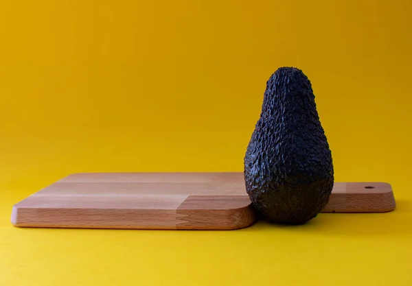 Kesme tahtasıyla sarı arkaplanda avokado