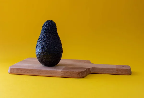 Kesme tahtasında sarı arka planda avokado