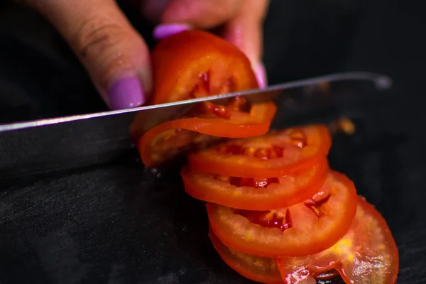 Manikürlü ellerle domates kesen bir kadın. Sağlıklı yaşam