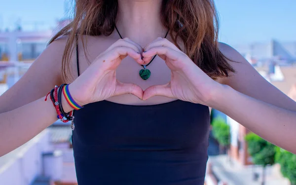 Elleriyle kalp yapan bir kız, lgtbi bilekliği.