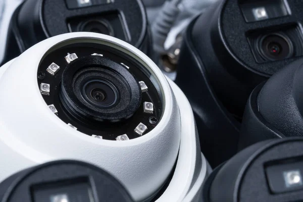 Close-up white security camera with black cameras nearby