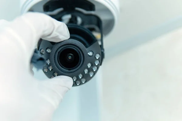 Close-up of the installation of a surveillance camera, a male hand in a white glove holds a surveillance camera