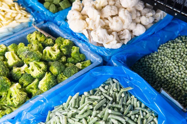 Assortment of frozen vegetables in a supermarket fridge.