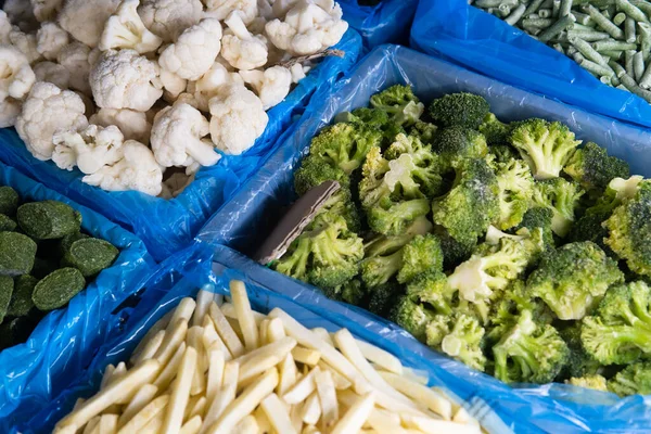 Assortment of frozen vegetables in a supermarket fridge.