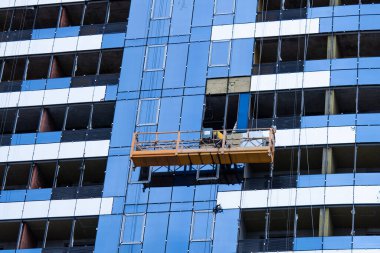 Yüksek bina inşaatı. Yüksek katlı bir binanın kurulumu. Beton, çelik, cam ve insan birlikte..