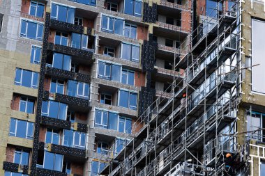 Yeni bir binanın arka planına karşı cam cephe panellerinin inşası ve kurulumu.