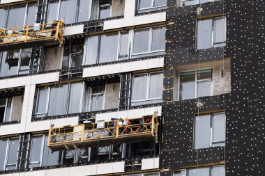 Müteahhit inşaat halindeki bir evin dış cephesini pencerelerin etrafında mineral yalıtım malzemesi ile yalıtımlı hale ediyor..