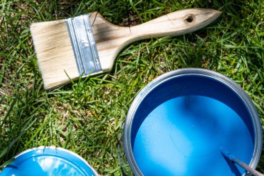 Blue paint can and brush from above on green background