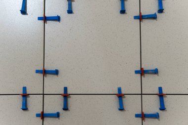 Installing ceramic floor tile in new construction work by tile glue for good adhesion.