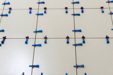 Installing ceramic floor tile in new construction work by tile glue for good adhesion.