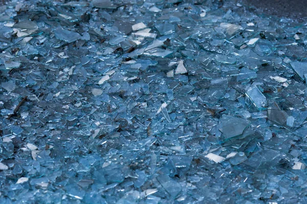 Shattered Glass. Background as broken pieces or crocks of white glass on the ground outdoors. Pine needles between glass pieces