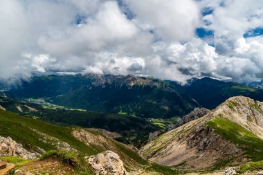 Latemarscharte dağ geçidinden Dolomites 'teki Latemar dağ grubunda kayalık dağ tepeleri ve daha alçak tepelerin karışımı otlaklarla kaplı.