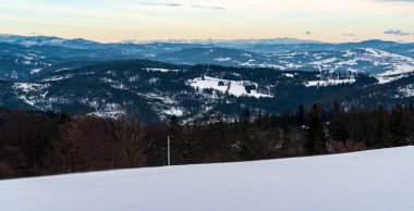 Hills of Beskids mountains and mountain peaks of Tatra mountains on the background from Cieslar hill summit in winter Beskid Slaski mountains on polish - czech borders