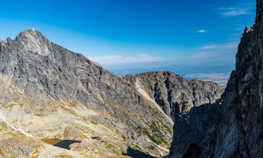 Slovakya 'nın Vysoke Tatry dağlarında Priiecne sedlo' nun yukarısındaki az göllü Mala Studena dolina, Teryho chata ve Lomnicky dikişli dağ zirvesi mavi gökyüzü ile güzel bir gün boyunca