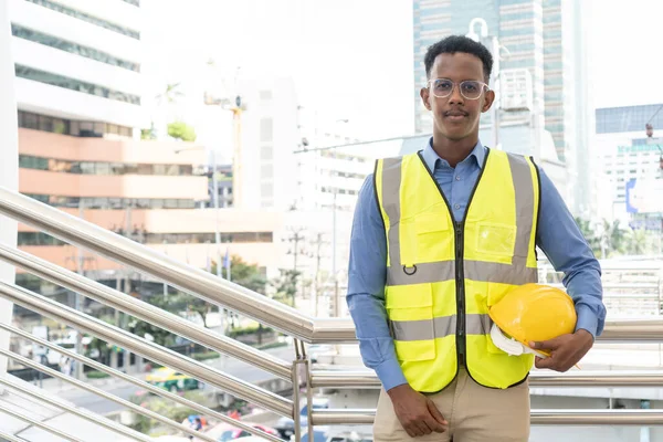 Engineer Worker Wearing Hard Hat. Happy Successful. Portrait of young African man wearing yellow hard hat helmet. Worker Wearing Safety Vest and Hard Hat