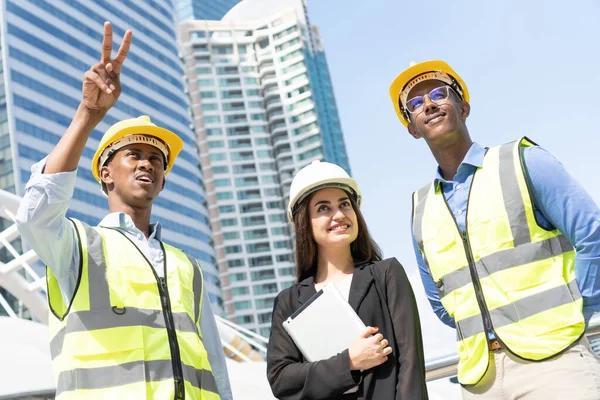 Mühendis, İşadamı ve kadın sekreter tablet kullanarak çalışma ekibi oluşturuyorlar. Mühendisler çalışma planı hakkında konuşuyorlar. Mühendis ve mimar ekibi inşaatı kontrol ediyor. 