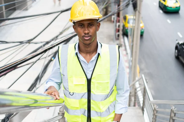 Portrait of young African man wearing yellow hard hat helmet. Worker Wearing Safety Vest and Hard Hat