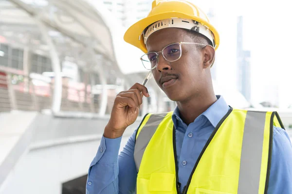 Engineer Worker Wearing Hard Hat. Happy Successful. Portrait of young African man wearing yellow hard hat helmet. Worker Wearing Safety Vest and Hard Hat