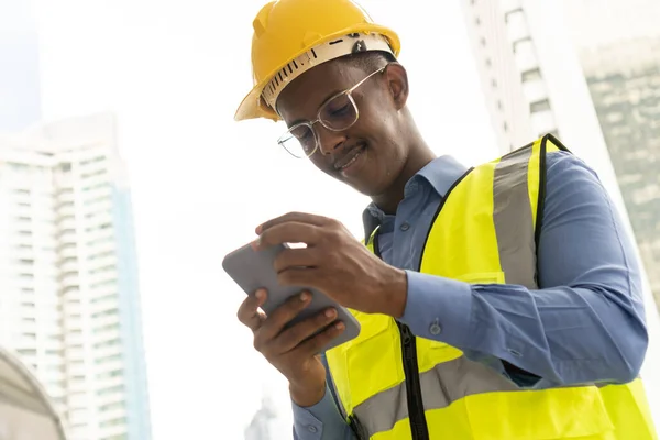 Engineer Worker Wearing Hard Hat. Happy Successful. Portrait of young African man wearing yellow hard hat helmet. Worker Wearing Safety Vest and Hard Hat