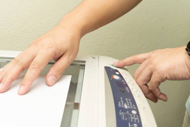 Ofis çalışanının elini kapat ve fotokopi makinesinin fotokopi odasında belge yazdırma işleminde kullanılmak üzere paneldeki kopyalama düğmesine bas