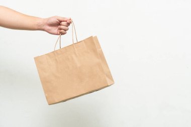 Beyaz arka planda izole edilmiş Kraft kağıt torba ile el. Dünyayı kurtarmak, küresel ısınmayı azaltmak.