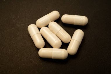 Siyah kağıt üzerinde hasta için beyaz kapsül. Reçeteli opioid oval haplar. Opioid krizi. Tıbbi beyaz kapsüller siyah arka planda izole edilmiş. Tedavi için kapsüller