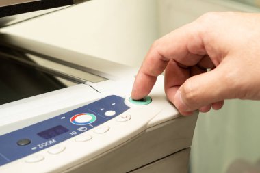 Ofis çalışanının elini kapat ve fotokopi makinesinin fotokopi odasında belge yazdırma işleminde kullanılmak üzere paneldeki kopyalama düğmesine bas