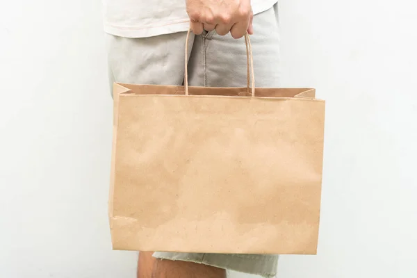 Hand with Kraft paper bag isolated on white background. save the world, reduce global warming