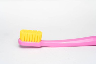 Pembe saplı diş fırçası, sarı fırça başı. Diş fırçası beyaz arkaplanda yakın plan.