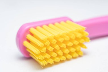 Pembe saplı diş fırçası, sarı fırça başı. Diş fırçası beyaz arkaplanda yakın plan.
