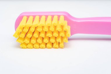 Pembe saplı diş fırçası, sarı fırça başı. Diş fırçası beyaz arkaplanda yakın plan.