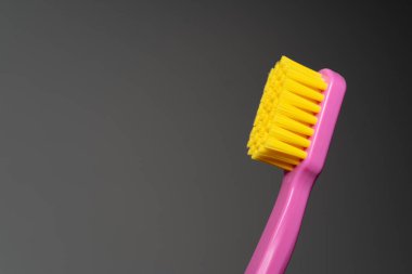 Pembe saplı diş fırçası, sarı fırça başı. Diş fırçası beyaz arkaplanda yakın plan.