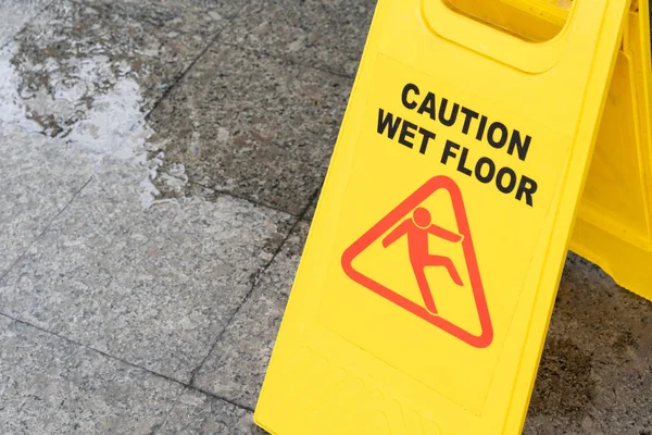 Yellow Caution slippery wet floor sign on the wet ground