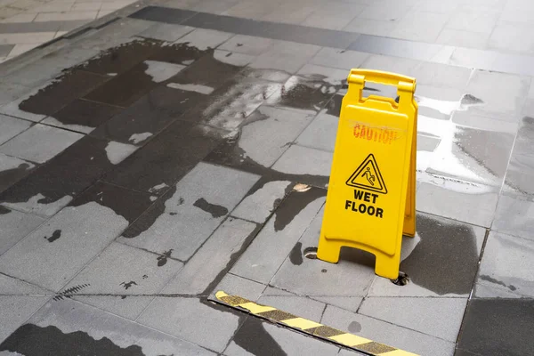 Yellow Caution slippery wet floor sign on the wet ground