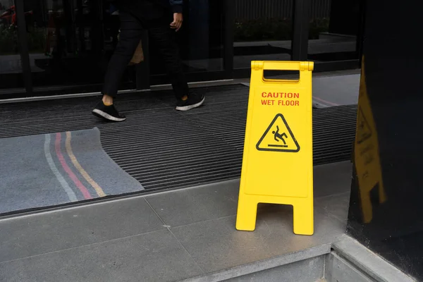 Yellow Caution slippery wet floor sign on the wet ground