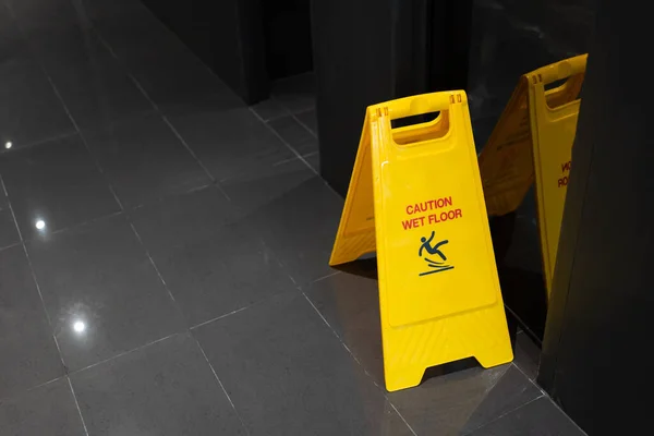 Yellow Caution slippery wet floor sign on the wet ground