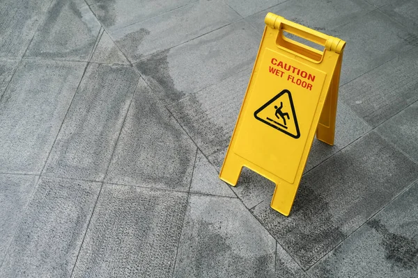 Yellow Caution slippery wet floor sign on the wet ground