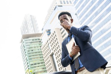 Şehirdeki iş adamları. Yakışıklı bir iş adamının portresi. Modern iş adamı. Kendine güvenen, takım elbiseli ve gözlüklü genç bir adam arka planda şehir manzarasıyla dışarıda dikilirken.