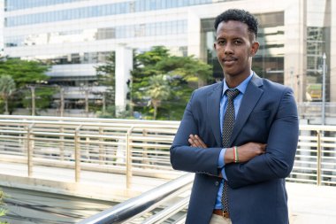 Şehirdeki iş adamları. Yakışıklı bir iş adamının portresi. Modern iş adamı. Kendine güvenen, takım elbiseli ve gözlüklü genç bir adam arka planda şehir manzarasıyla dışarıda dikilirken.