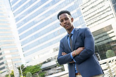 Şehirdeki iş adamları. Yakışıklı bir iş adamının portresi. Modern iş adamı. Kendine güvenen, takım elbiseli ve gözlüklü genç bir adam arka planda şehir manzarasıyla dışarıda dikilirken.